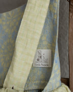 Linen flower dress for little girl with 'Little Noele' label on a wooden ladder