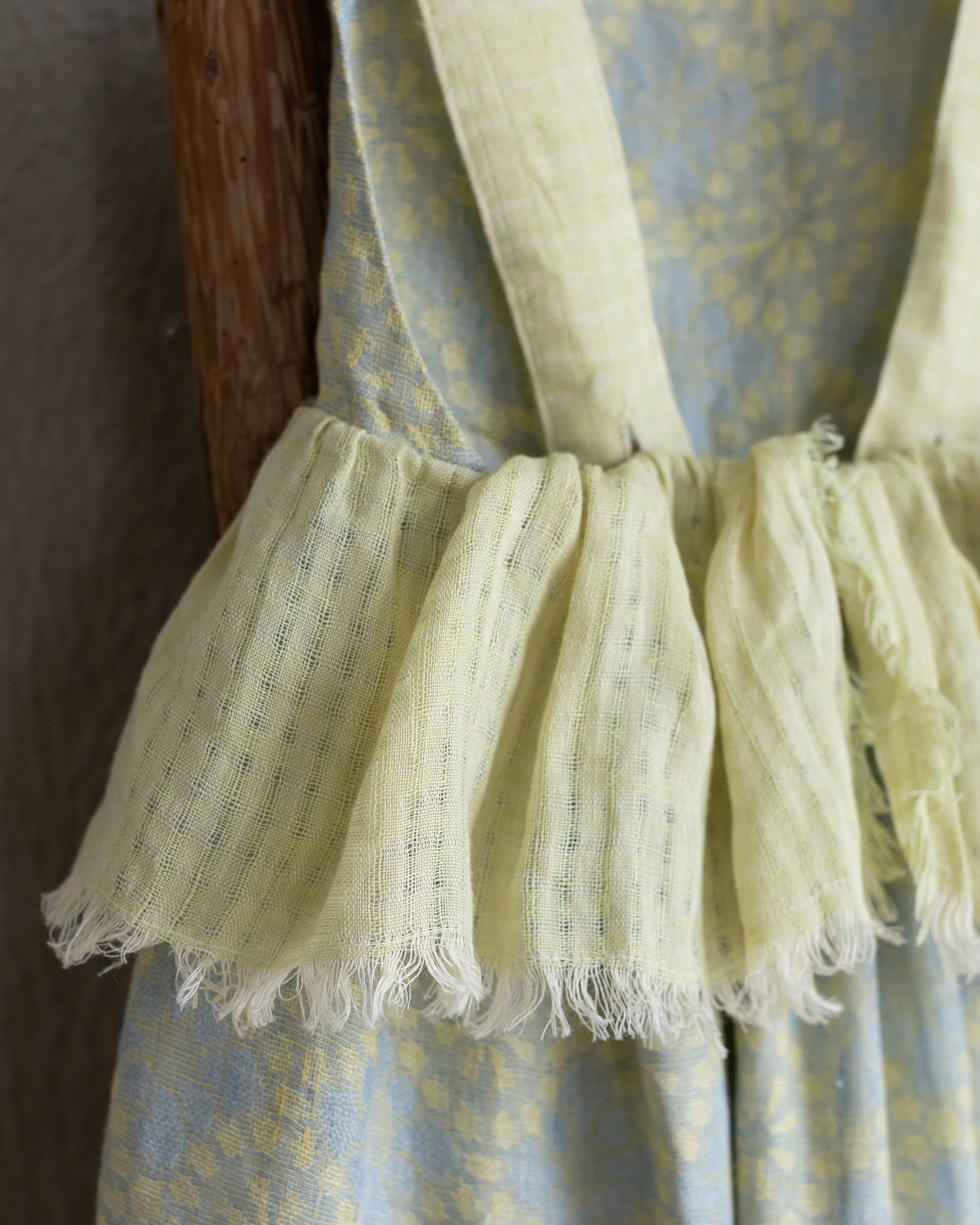 Light yellow linen dress with ruffled hem on a plain background