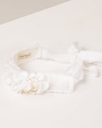 White linen headband with flowers made from fabric scraps on a light beige background