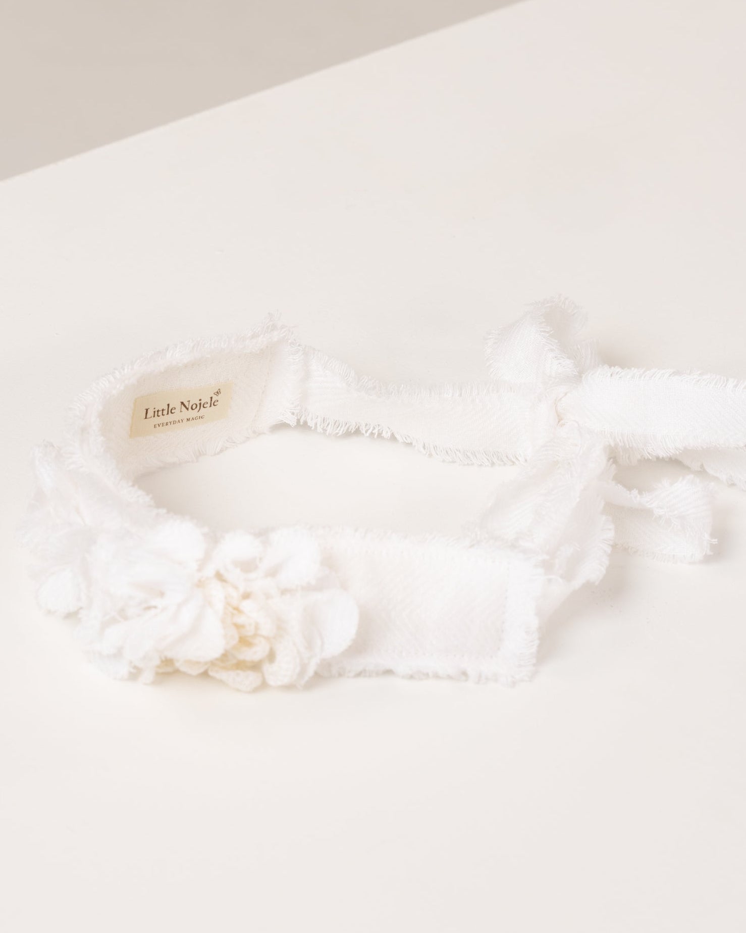 White linen headband with flowers made from fabric scraps on a light beige background