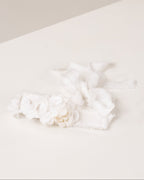 White linen headband with flowers made from fabric scraps on a light beige surface