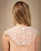 Young girl wearing a crocheted white linen collar over a beige top against a brown background