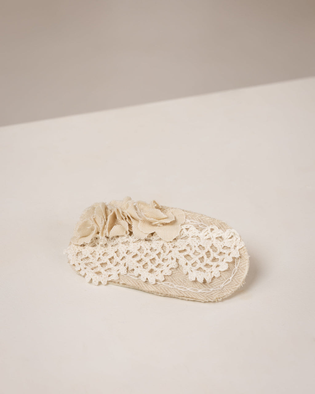 Beige hair clip with crocheted lace on a light beige background