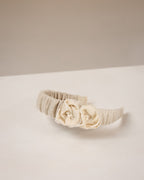Beige linen headband with flowers from fabric embellishments on a white surface