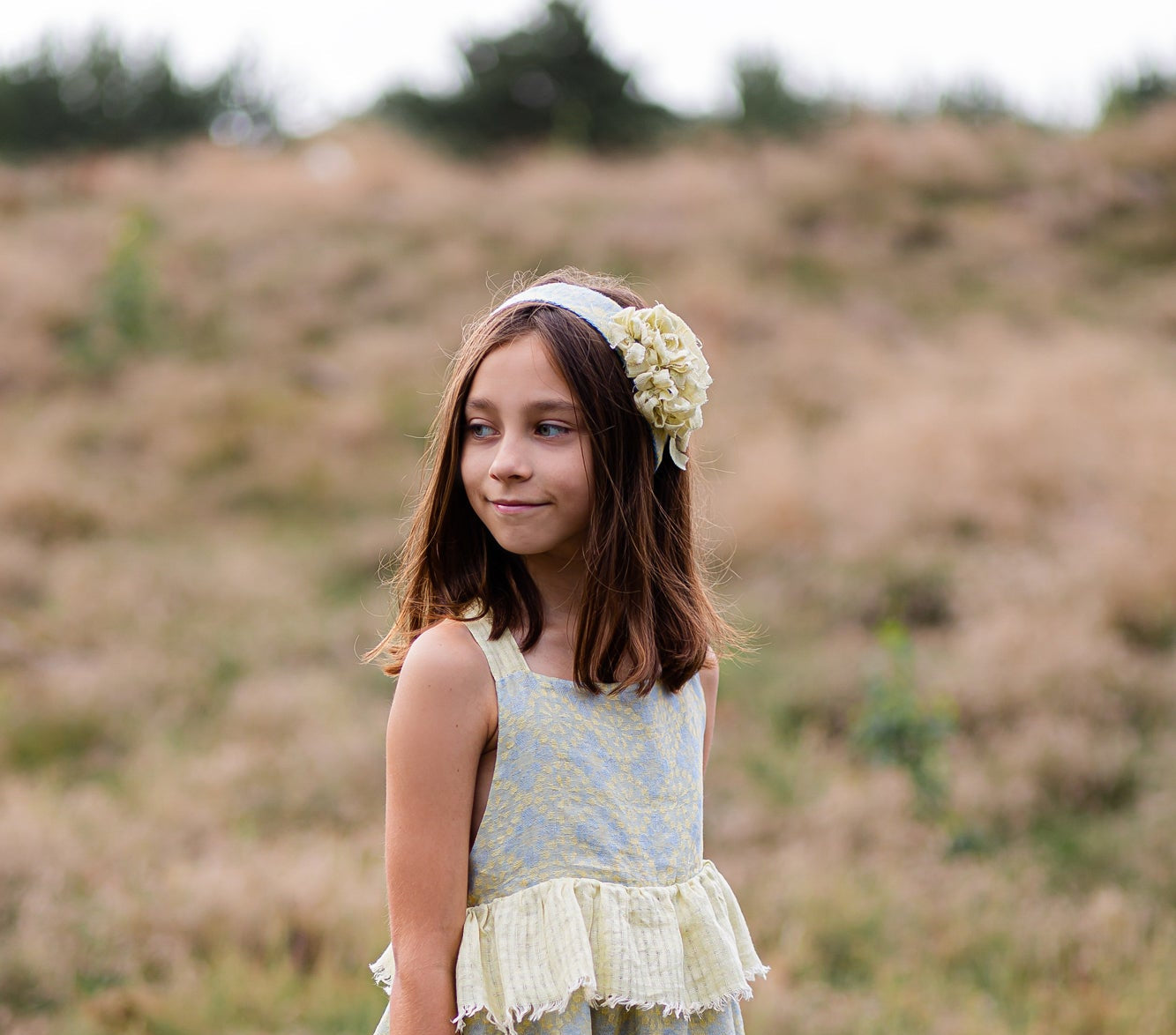 Young girl in a floral linen dress standing in a field